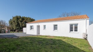 A single-story white building with a tiled roof, a small front porch, and a grassy yard.