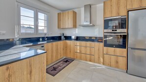 A modern kitchen with wooden cabinets, stainless steel appliances, and a large window providing natural light.