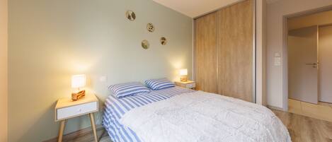 Quarto com cama, mesas de cabeceira, guarda-roupa e parede decorada com pratos.
