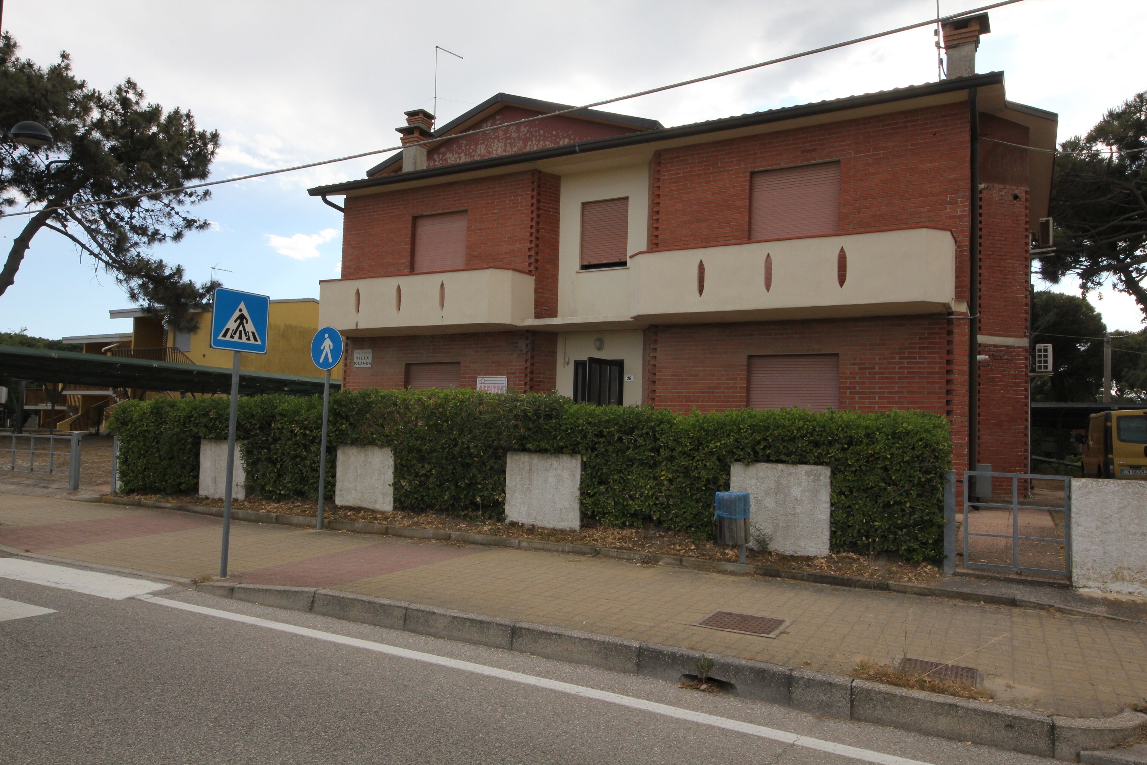 A two-story residential building with a brick facade, a pedestrian crossing sign, and a gated entrance.