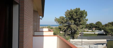 A balcony with a view of a tree and a distant landscape.