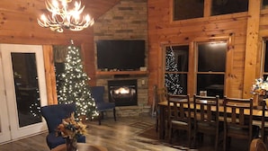 Interior acogedor de una cabaña de madera con chimenea, un árbol de Navidad y un comedor.