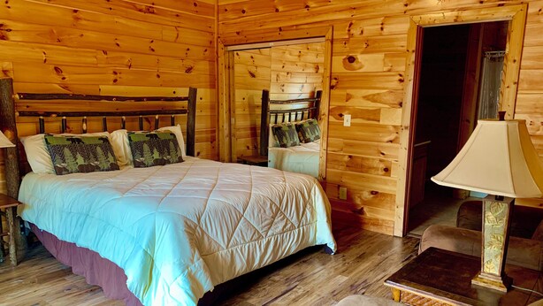 Une pièce dans un chalet en bois, comprenant un lit, une chaise, une table et une lampe.