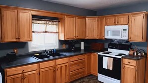 Una cocina con armarios de madera, un microondas, una estufa y un fregadero.