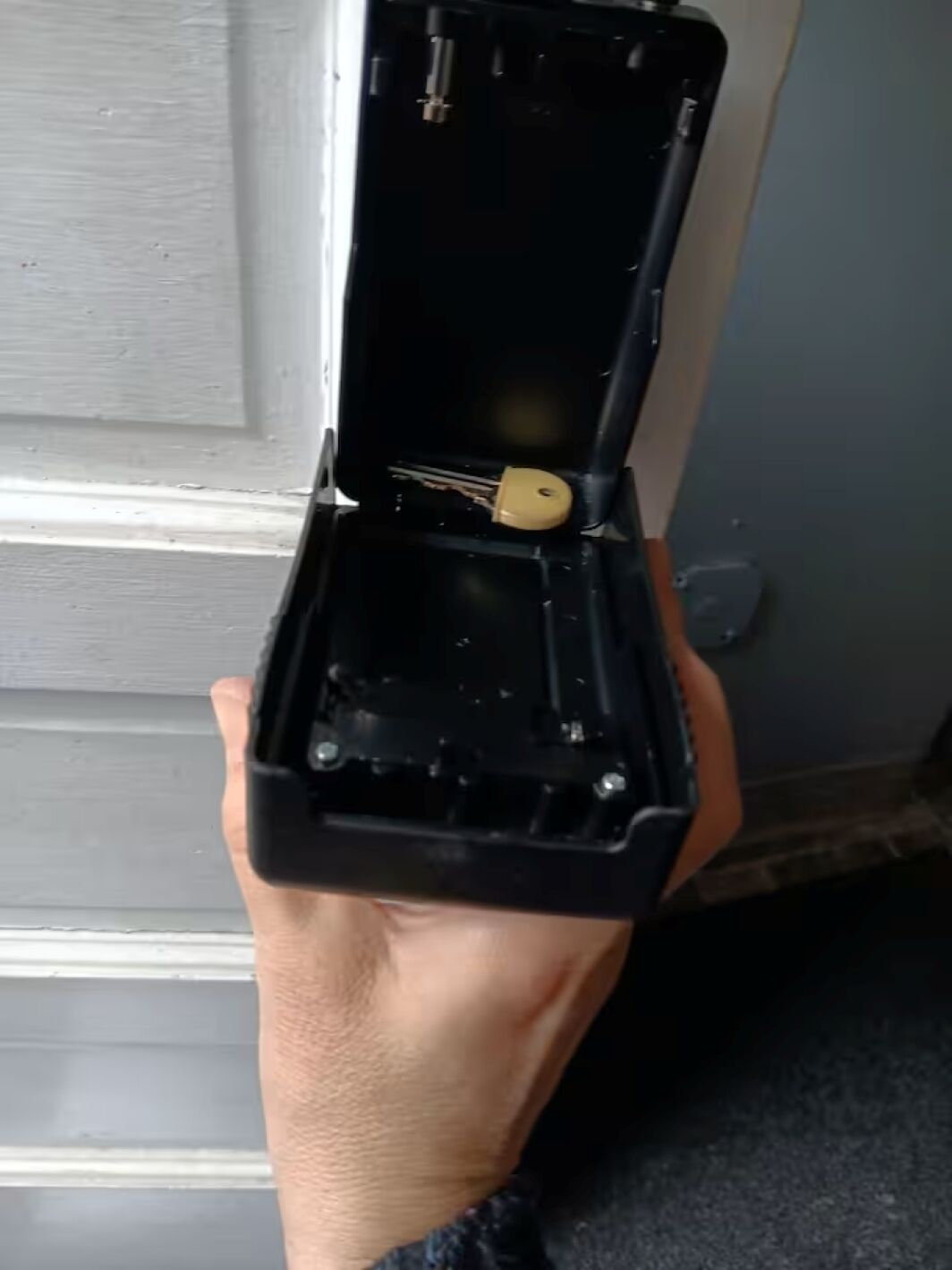 A hand holding an open jewelry box with a ring inside.
