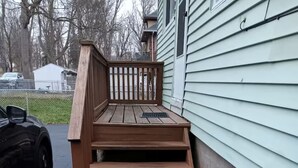 Una serie de escalones de madera al aire libre que llevan a la puerta principal de una casa.