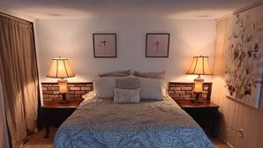 Un dormitorio con una cama grande, dos lámparas de noche, un cabecero con diseño de ladrillo y papel tapiz floral.