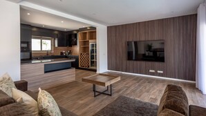 A modern living room with a large flat-screen TV, a wooden coffee table, and a sofa.