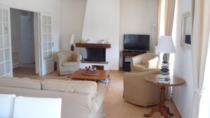 A living room with a sofa, two armchairs, a coffee table, a fireplace, a television, and a lamp. - Beautiful house, very well located, sleeps 4 to 10, with swimming pool and air conditioning. (Saint-Raphaël)
