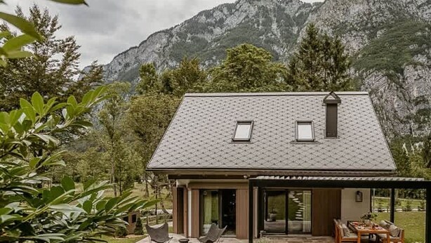 Ein modernes Haus mit Terrasse, Essbereich und Blick auf Berge.