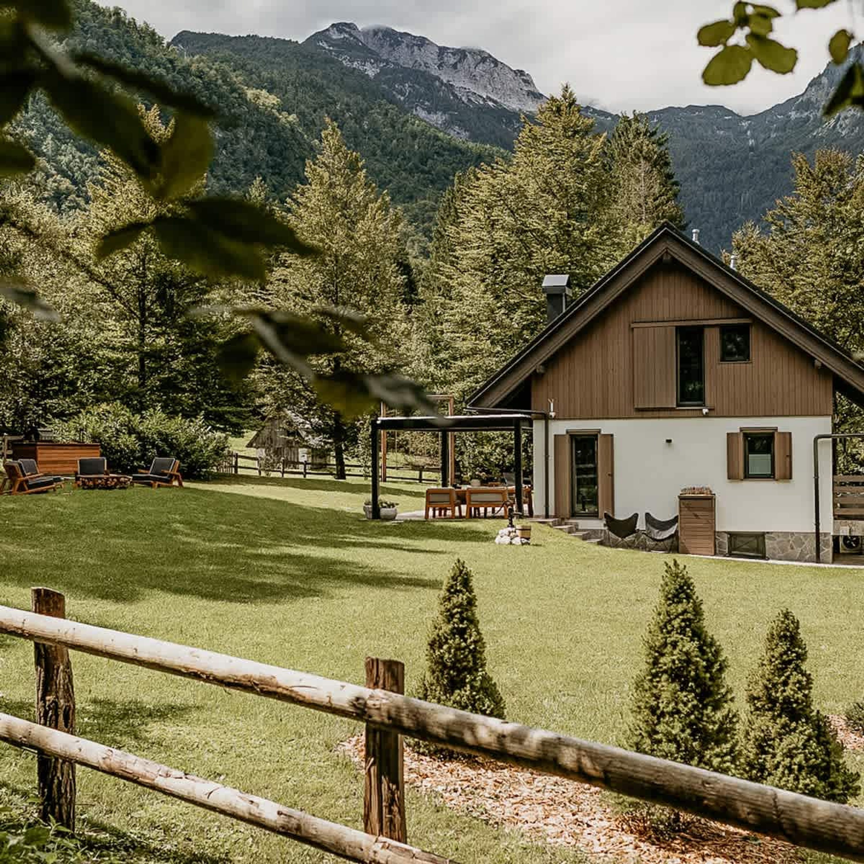 Ein modernes Haus mit geneigtem Dach, umgeben von einem gepflegten Rasen und einem Holzzaun.
