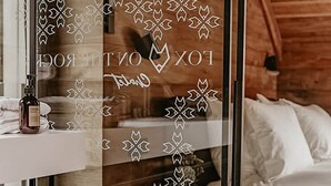 Ein modernes Schlafzimmer mit Holzboden, einer Glastür mit Schneeflockenmuster und einem Bett mit weißer Bettwäsche.