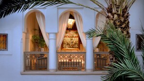A building with three arched windows, a central chandelier, and a palm tree in the foreground. - Charming Riad and Douiria Swimming Pool Private (Marrakech)