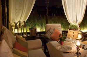 An outdoor seating area with a table set for dining, a sofa with cushions, and a potted plant.