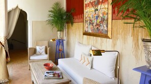 A room with a sofa, a chair, a table with a bowl, a plant, and a painting on the wall. - Charming Riad and Douiria Swimming Pool Private (Marrakech)