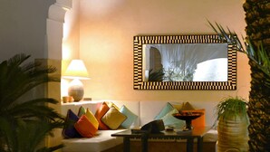 A cozy room with a sofa, colorful cushions, a table, a lamp, and a decorative mirror. - Charming Riad and Douiria Swimming Pool Private (Marrakech)