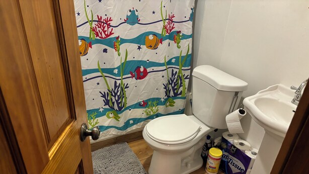 Un baño con inodoro, lavabo y cortina de ducha con temática marina.