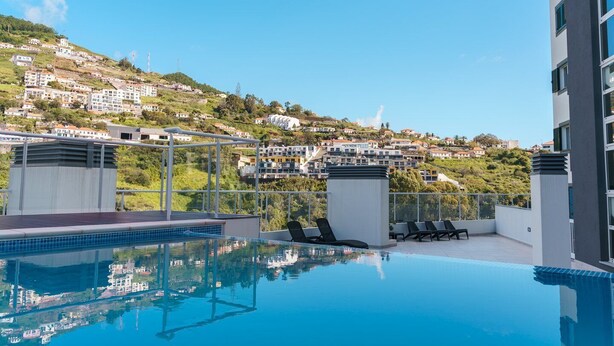 A rooftop pool with a clear view of a hillside town. - GuestReady - A sweet escape in Caniço (Caniço)