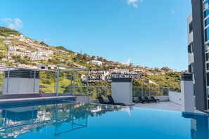 A rooftop pool with a clear view of a hillside town. - GuestReady - A sweet escape in Caniço (Caniço)