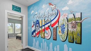 A hallway with a mural featuring a space shuttle, a cow, and a city skyline. - Texas Cities Themed House, Hot tub. Don't Mess With Texas (Houston)