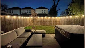 An outdoor patio area with a wooden fence, a small tree, and a hot tub. - Texas Cities Themed House, Hot tub. Don't Mess With Texas (Houston)
