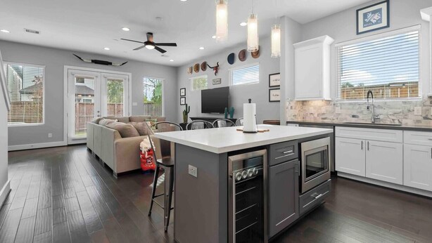 A modern kitchen with white cabinets, a central island, and a dining area with a sofa. - Texas Cities Themed House, Hot tub. Don't Mess With Texas (Houston)