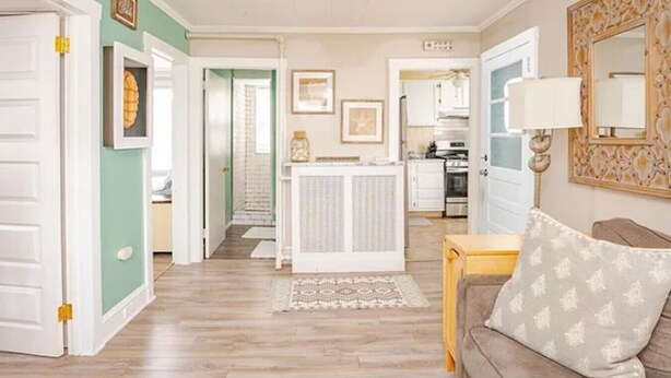 A spacious living room with a ceiling fan, a sofa with patterned cushions, and a kitchen in the background. - Cozy 2BR with Bunk Beds, Steps to Boardwalk (Ocean City)
