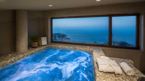 Ein Wellnessbereich mit Whirlpool, Handtüchern und Meerblick.