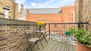 Eine Holzterrasse mit Tisch und Stühlen, einem Blumentopf und einer Ziegelmauer.