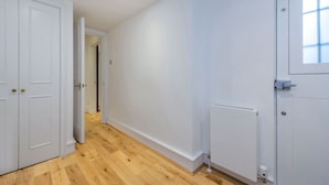 A hallway with white walls, wooden flooring, and a radiator. - The Fairytale - Fitzrovia - by Frankie Says (London)