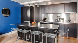 A modern kitchen with a central island, stainless steel appliances, and bar stools.