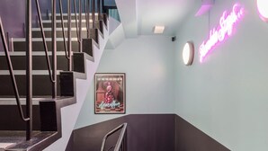 Eine Treppe mit Metallgeländern und einem Neonzeichen an der Wand.