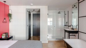A modern bedroom with a bed, bedside table, and a red accent wall. - The Instagood Penthouse - Covent Garden - by Frankie Says (London)