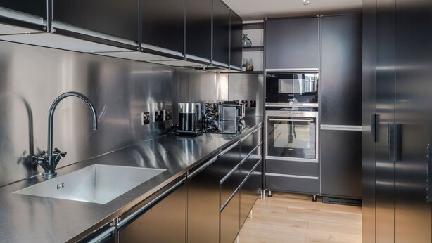A modern kitchen with stainless steel appliances, a large sink, and a built-in oven. - The Instagood Penthouse - Covent Garden - by Frankie Says (London)