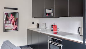Een moderne keuken met donkere kastjes, een inbouwmagnetron, een koffieapparaat en een spoelbak.