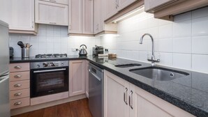 Een moderne keuken met lichte kastjes, een zwarte aanrechtplaat, roestvrijstalen apparatuur en een dubbele spoelbak.