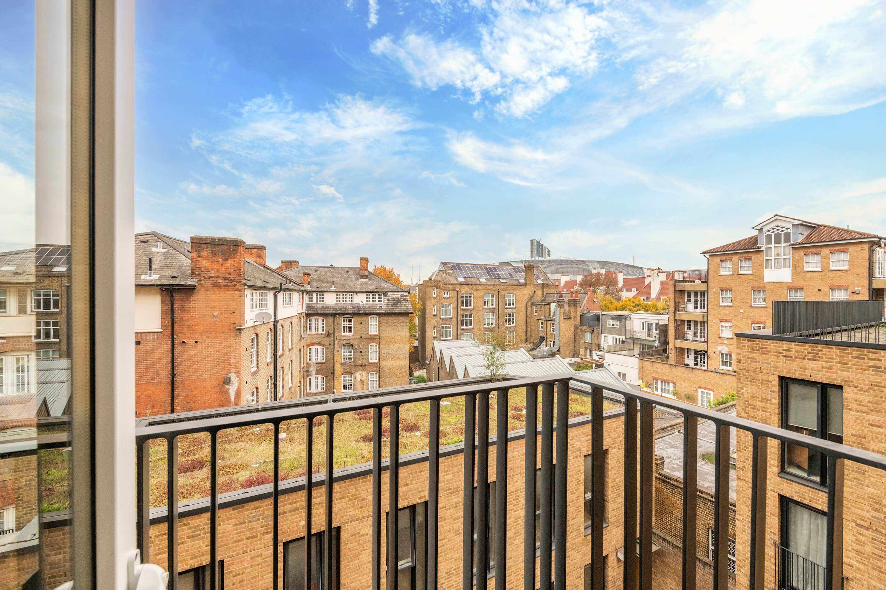 A view from a balcony overlooking a row of brick buildings with a clear sky.