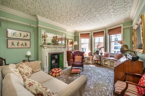 Ein traditionell eingerichtetes Wohnzimmer mit Kamin, grünen Wänden und klassischen Möbeln.