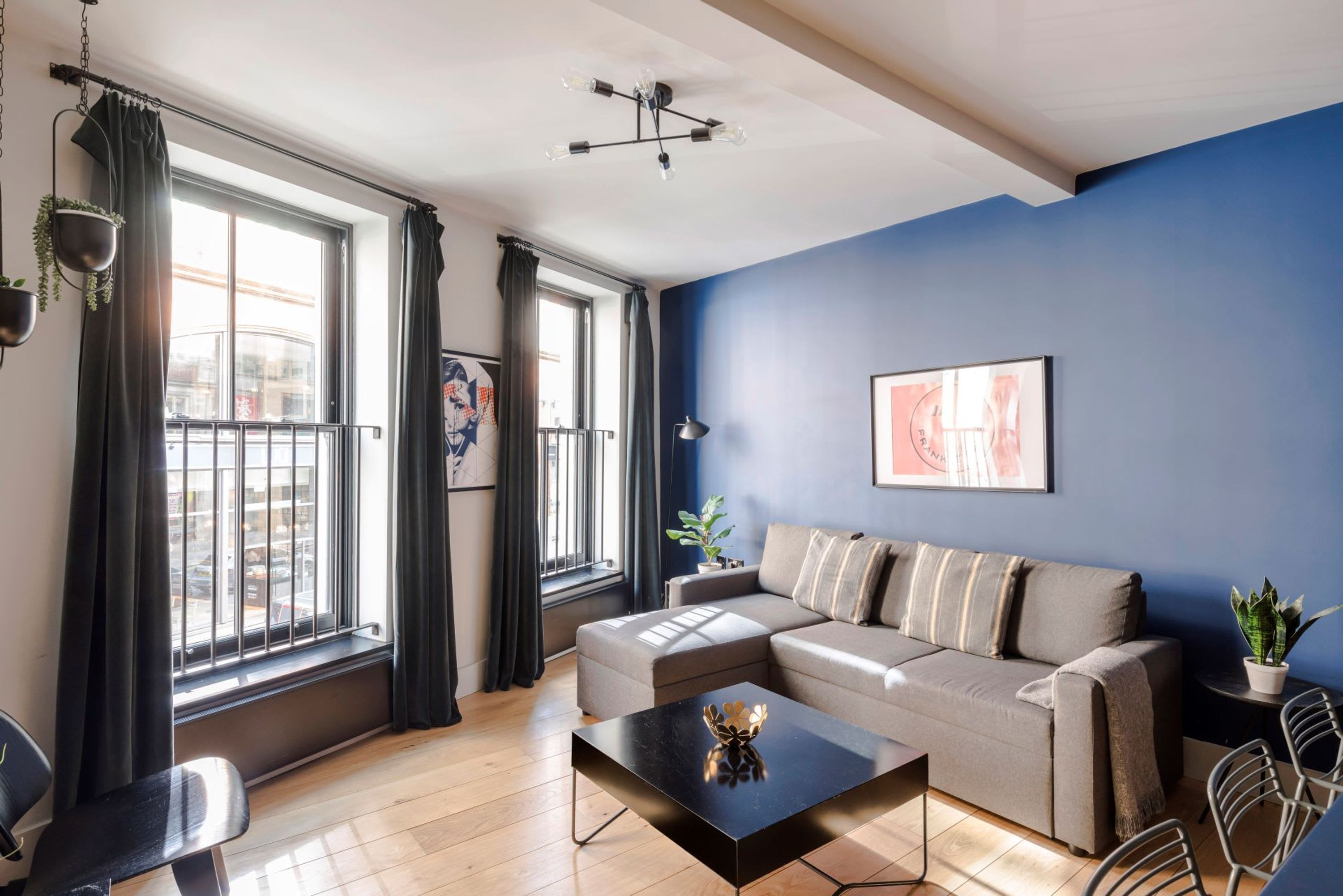 A modern living room with a sofa, a coffee table, and a view of the city through large windows.