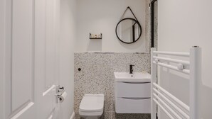 Un baño con inodoro, lavamanos, espejo y toallero.