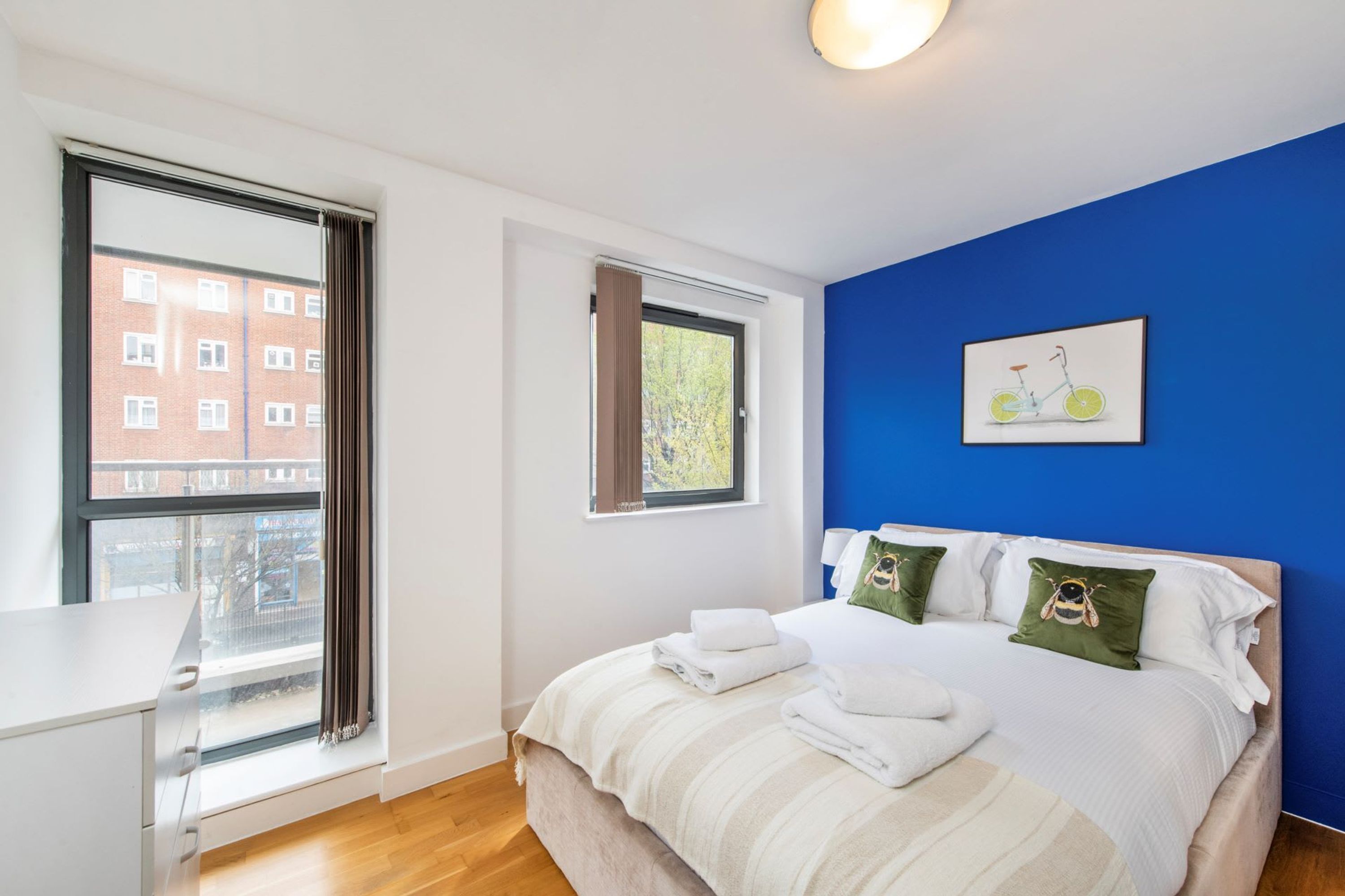 A bedroom with a bed, a window, and a blue wall.