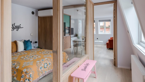 A modern bedroom with a bed, a bench, a mirror, and a view of a dining area. - Casa Emilio - Soho - by Frankie Says (London)