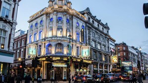 A historic building with a prominent curved corner, large windows, and illuminated signage for a theater. - Casa Emilio - Soho - by Frankie Says (London)