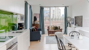 A modern apartment with a kitchen, dining area, and living room. It features a large window with curtains, a sofa, and a coffee table. - A Starry Starry Night - Borough - by Frankie Says (London)