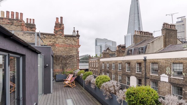 A rooftop terrace with a view of the Shard, featuring a seating area and a brick building. - A Starry Starry Night - Borough - by Frankie Says (London)