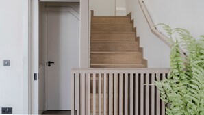 A wooden staircase with a handrail, a white door, and a plant to the right. - Parkside House - Regent s Park - by Frankie Says (London)