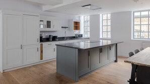 Une cuisine moderne avec des meubles blancs, un îlot central et un coin repas comprenant une table et des chaises.