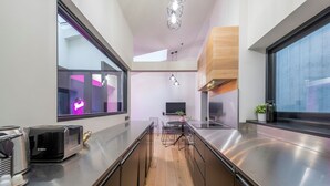 A modern kitchen with stainless steel appliances, a wooden floor, and a central island with seating. - The Insta Playhouse - Covent Garden - by Frankie Says (London)