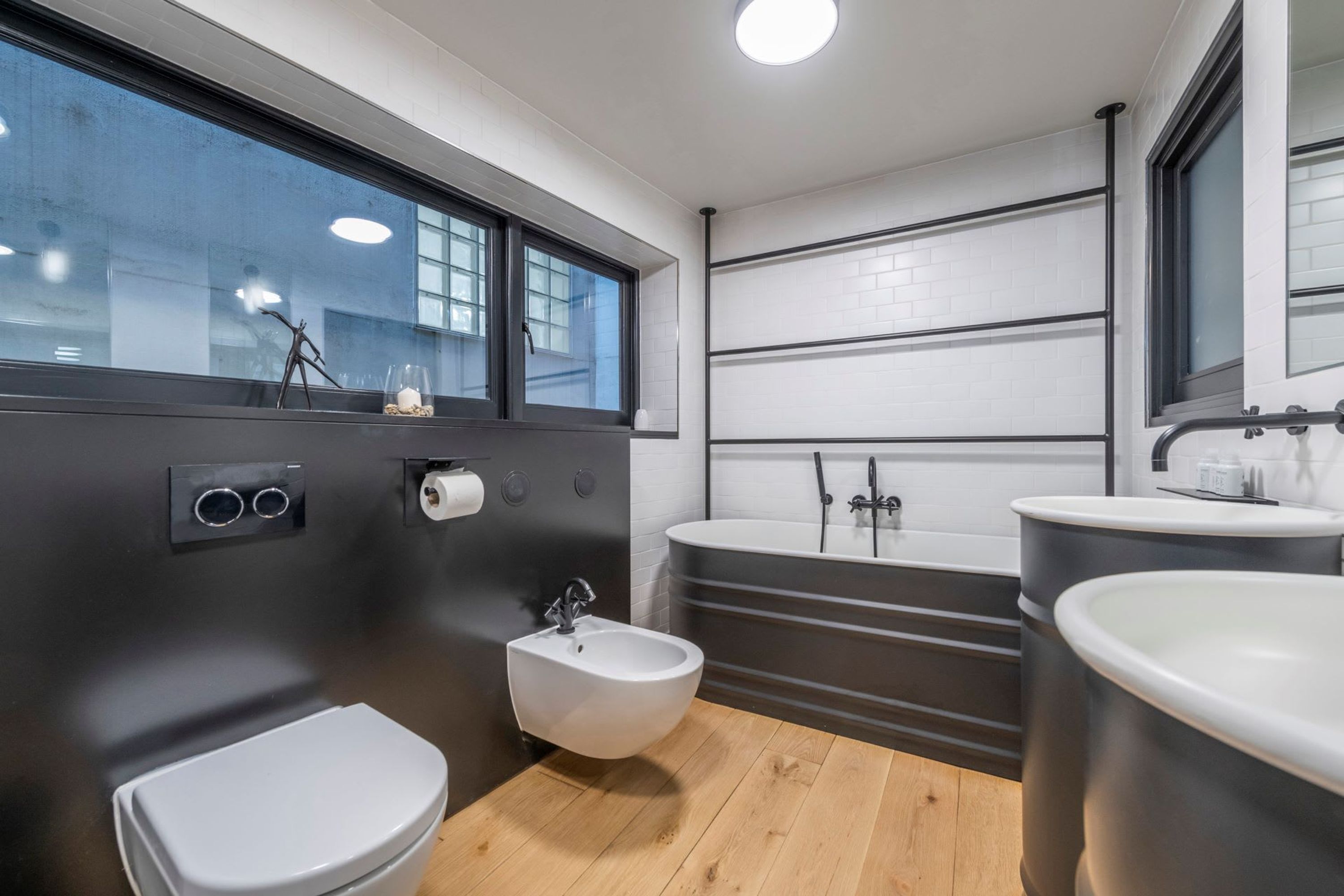 Une salle de bain moderne équipée d’un bidet, de toilettes et de deux lavabos.