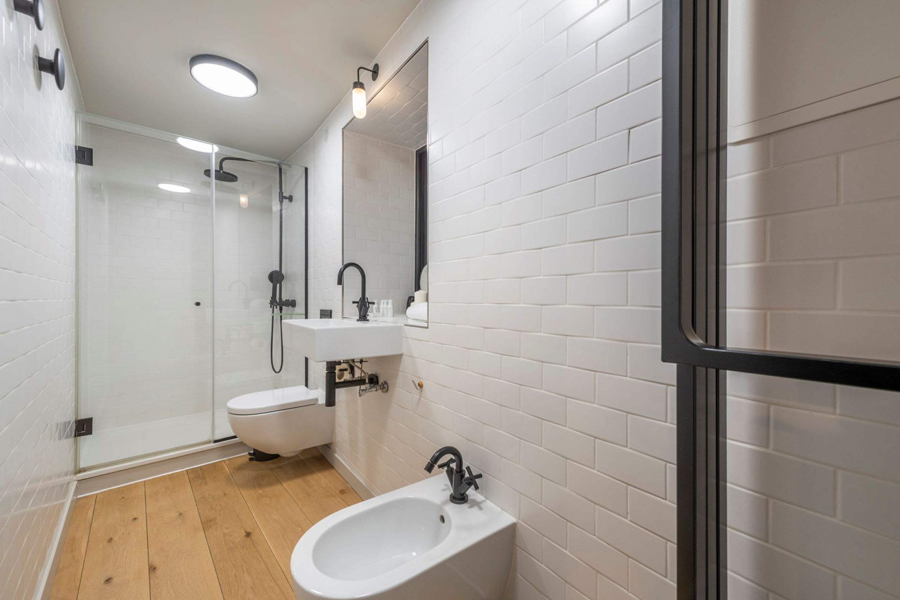 Une salle de bain moderne avec une douche à parois de verre, un lavabo blanc et un bidet.